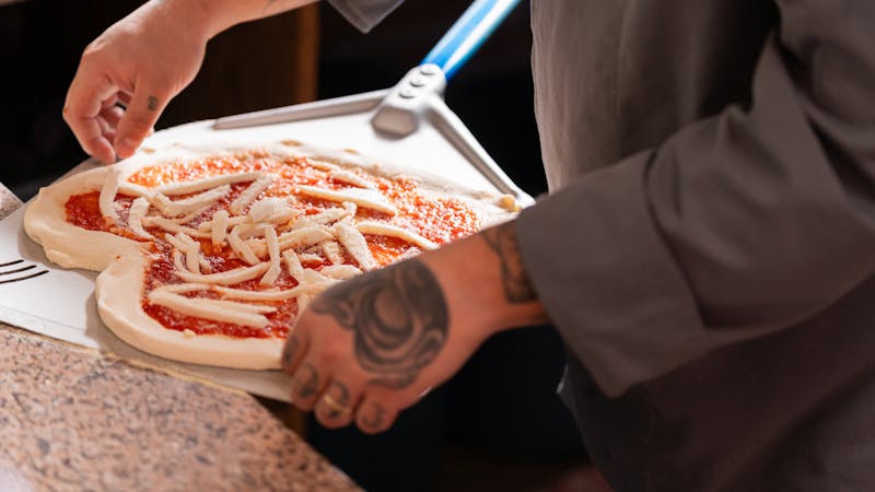 Pizza Ranch team members preparing ranch pizza with fresh ingredients